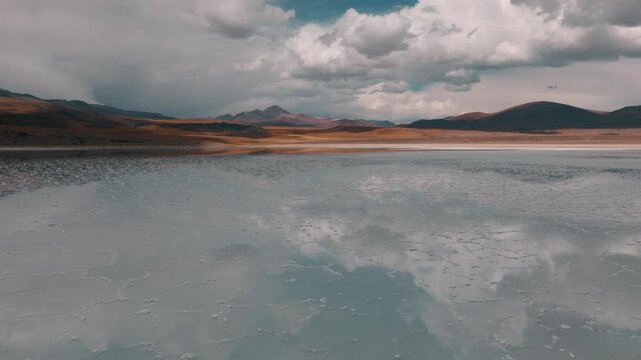 Aerial view of a turquoise Andean lagoon surrounded by volcanic peaks in the remote landscapes of Bolivia&rsquo;s Sud L&iacute;pez region.