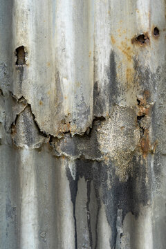 full-frame vertical abstract texture of a weathered, damaged, and heavily corrugated metal sheet, with broken surfaces, dark water stains, and subtle rust spots eg for grungy industrial backgrounds.