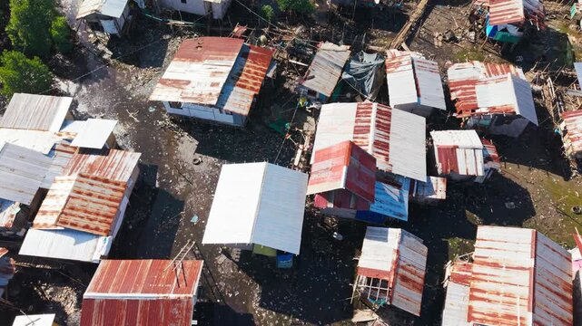 Rusty metal rooftops surround flooded coastal homes under bright tropical sun