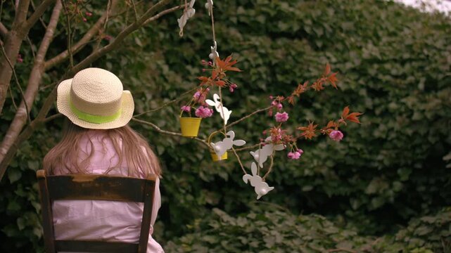 Woman wearing Easter bonnet and sits by easter decorations on blossom tree