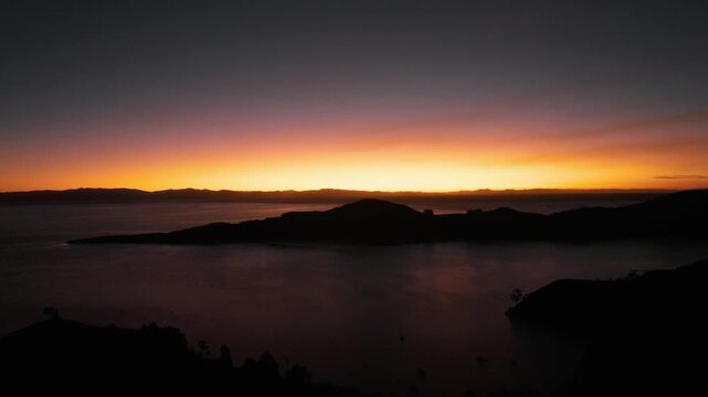 Drone view of a spectacular sunset over the islands of Lake Titicaca. Golden light bathes the Andean landscapes and tranquil waters of the world&rsquo;s highest navigable lake.
