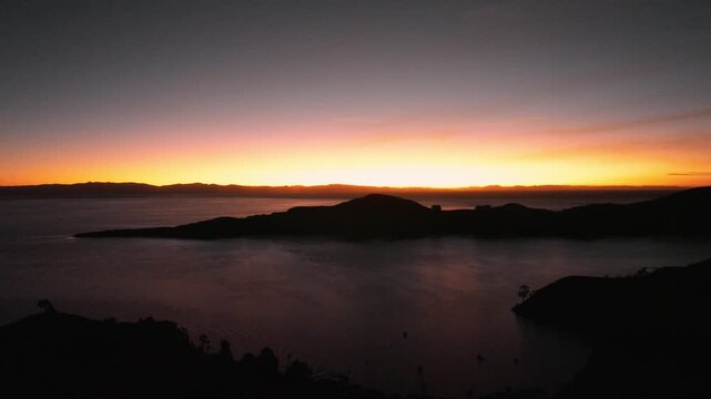 Drone view of a spectacular sunset over the islands of Lake Titicaca. Golden light bathes the Andean landscapes and tranquil waters of the world&rsquo;s highest navigable lake.