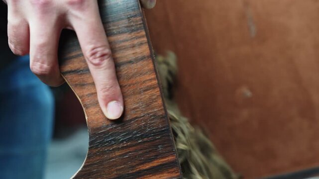 male hands pouring raw dry agarwood chips from a dark wooden bowl into a container. The fragrant oud pieces fall with rapid motion blur indoors under soft natural daylight.
