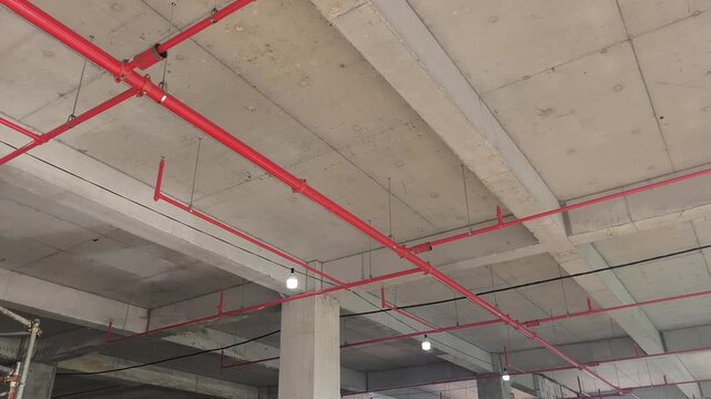Workers install a fire sprinkler pipe network at a construction site. Fabricated to precise engineering designs, this vital system delivers water to suppress initial blazes before firefighters arrive.