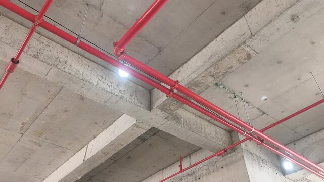Workers install a fire sprinkler pipe network at a construction site. Fabricated to precise engineering designs, this vital system delivers water to suppress initial blazes before firefighters arrive.