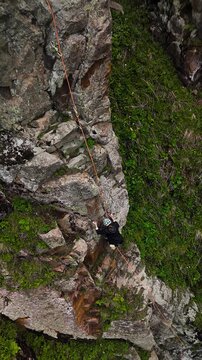 Man athlete climbing on the high rock in the mountains