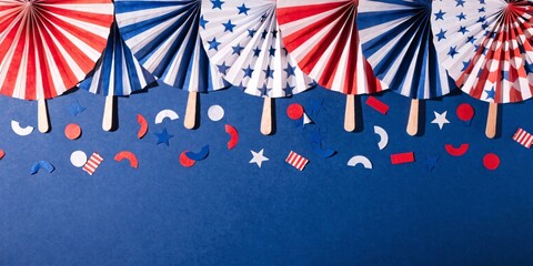 Obraz premium Vibrant 4th of July Independence Day decorations, folded paper fans, scattered festive confetti