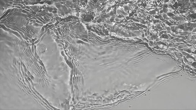 Pure water with reflections sunlight in slow motion. Water surface texture top view. Sun and shadows. Motion clean swimming pool ripples and wave.