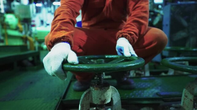 Trabajador industrial girando una v&aacute;lvula o manivela en un entorno de construcci&oacute;n naval y maquinaria pesada, industria, trabajo t&eacute;cnico, mantenimiento, ingenier&iacute;a y operaci&oacute;n de equipos