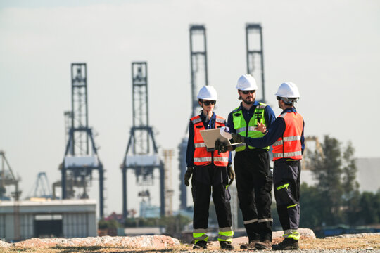 civil engineers and technical team conducting a structural integrity assessment of maritime infrastructure at a commercial shipyard, verifying technical blueprints for vessel maintenance.