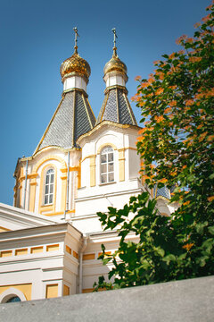 orthodox church with golden domes surrounded by trees on sunny day