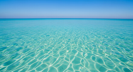 Obraz premium Crystal clear turquoise ocean water with sunlight reflections on surface