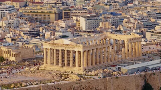 Golden hour light illuminating the parthenon temple and the ancient ruins on the acropolis hill, with the sprawling cityscape of athens, greece, spreading out into the background
