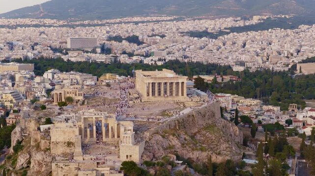 Iconic acropolis of athens featuring the parthenon temple, a unesco world heritage site, sitting on a rocky outcrop above the sprawling city with tourists visiting the ancient citadel