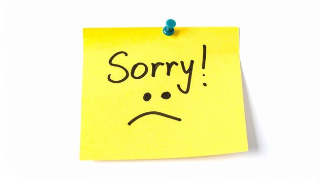 A bright yellow sticky note pinned to a white background featuring a handwritten sorry message and a sad face drawing expressing apology.