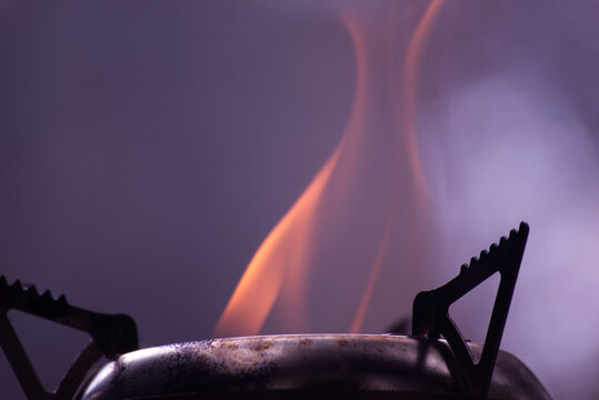 Well used Portable wood stove burning wood with a large red flame erupting out from within the chamber. Making coals for a quick outdoor grilled snack