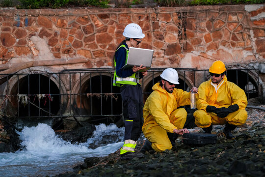 Engineering team in protective gear conducting an environmental audit, water quality sampling, and site survey at an industrial drainage outfall to ensure regulatory compliance.