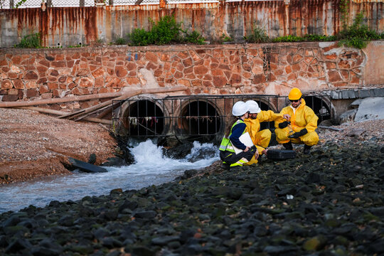 Engineering team in protective gear conducting an environmental audit, water quality sampling, and site survey at an industrial drainage outfall to ensure regulatory compliance.