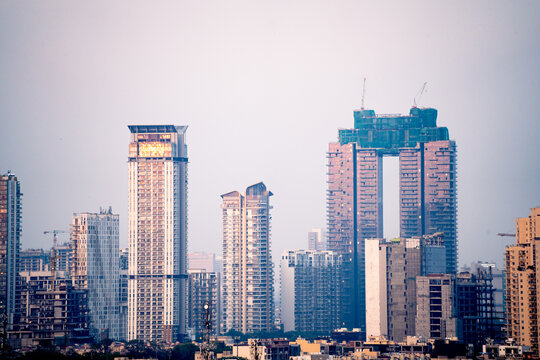 Aerial drone shot showing high rise skyscrapers under construction and completed cityscape of gurgaon delhi noida at dusk with sunlight reflected in India