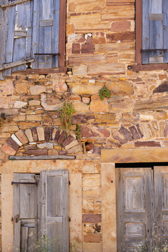 Red brown Thymiana limestone wall of an old mansion with windows and doors, Kampos architecture