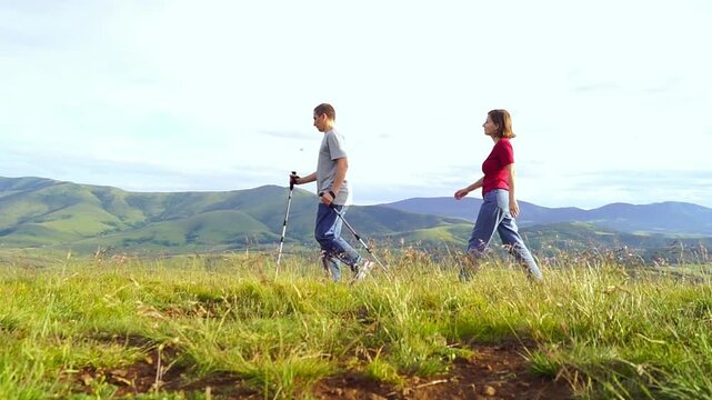 Two hikers follow an easy mountain route across open grass-covered terrain. Conveys beginner-friendly hiking culture, barrier-free outdoor participation, and approachable nature experiences.