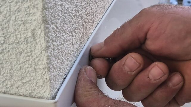 Close up video of inserting a screw into a metal roof flashing after drilling in slow motion