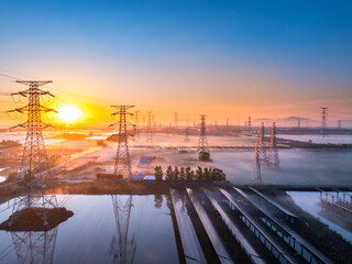 Power transmission towers and water reflections in the morning light at sunrise