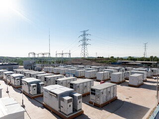 Fototapeta premium outdoor energy storage power station equipment with high voltage transmission towers under blue sky