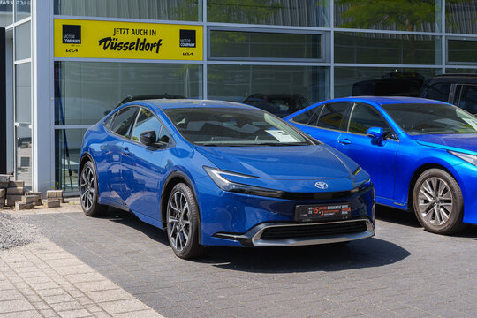 Dusseldorf, Germany - May 28 2026: New blue Toyota Prius electric car displayed outside a Toyota dealership with promotional signage