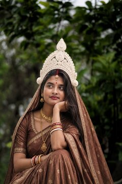 Traditional Bengali bride portrait with wedding topor crown looking away thoughtfully in nature