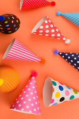 Obraz premium Colorful birthday caps on orange background. Top view.