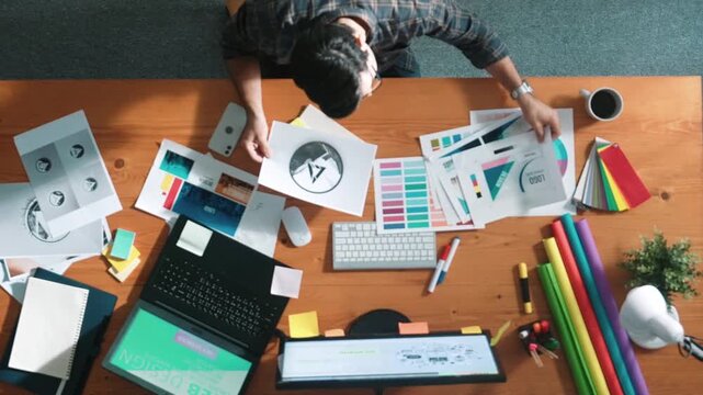 Top view of smart businessman hand choosing color palettes while designing logo graphic. Aerial view of professional interior designer design and select color theme by using color palettes. Symposium.