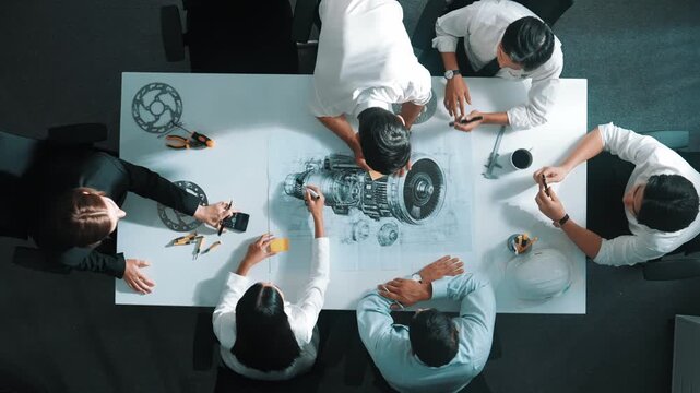 Top view of engineer team writing idea on sticky notes at meeting while discussing about turbine engine or electric generator at meeting table with metal gear, calculator and equipment. Alimentation.