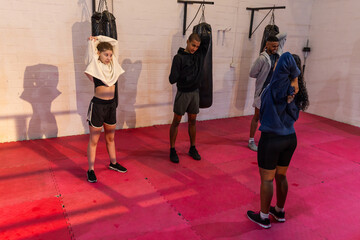 Diverse group with teenager stretching in athletic wear at boxing studio with heavy bags © wavebreak3