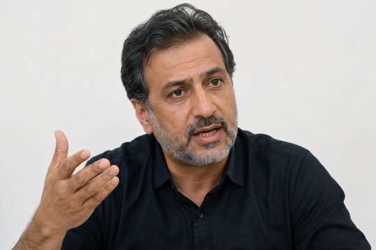 Middle Eastern businessman gesturing in office interview about corporate diversity and equality, middle aged corporate worker