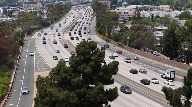 Heavy traffic congestion on Interstate freeway, commuting vehicles moving during rush hour in densely populated urban area of Los Angeles California