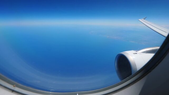 Blue sea water seen downwards and darken sky above horizon, look out from airliner window. Plane fly over Cantabrian Sea, just leave northern Spain area and head on France