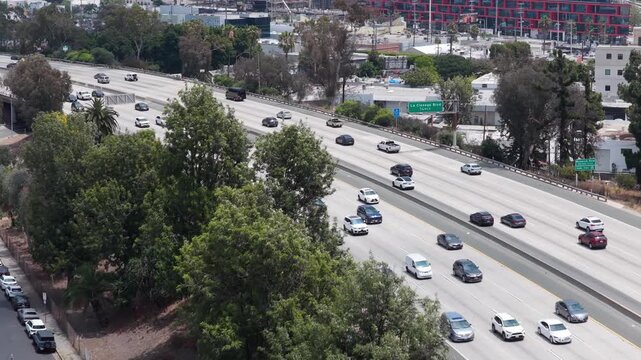 Cars commuting on interstate freeway with Los Angeles urban landscape in background, rush hour and American infrastructure development