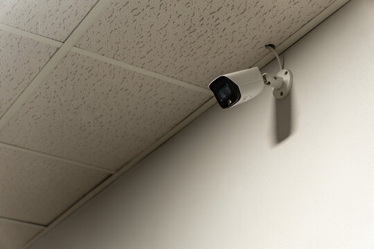 Modern CCTV Security Camera Mounted on Office Ceiling Corner for Surveillance and Monitoring