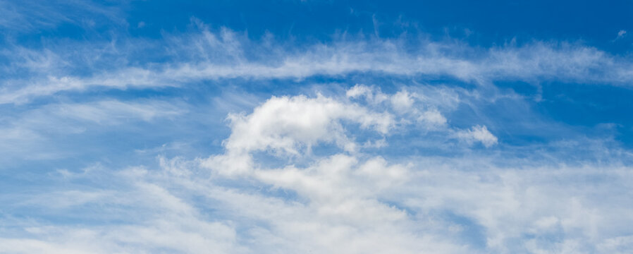 Panoramic bright blue sky with light cirrus clouds and small white cumulus at the bottom, fresh summer natural background