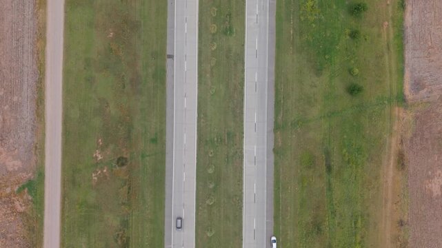 Top-down aerial view of a divided dual carriageway with two lanes in each direction, road traffic, transportation network, modern infrastructure, mobility and highway engineering