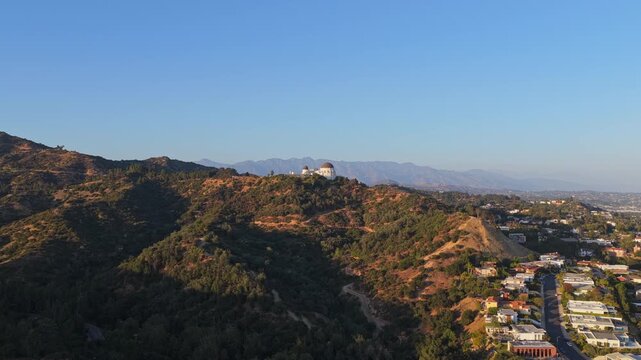 Morning light illuminating Griffith Observatory and Mount Lee, Los Angeles cityscape, Hollywood Hills, residential neighborhood on clear day in California
