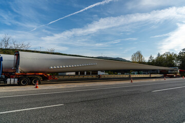 Fototapeta premium Oversized wind turbine blade transported on a specialized trailer along a highway. Renewable energy logistics, heavy haul transport and wind power infrastructure.