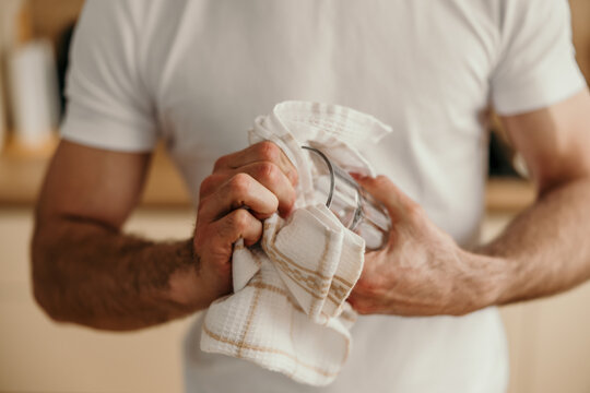 Man hands drying glass with kitchen towel