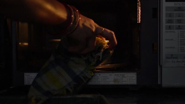 Taking Out Freshly Baked Cake From Microwave Oven Close Up. Removing Hot Cake Mold From Lit Electric Oven After Cooking. 