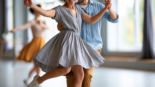Anonymous couple swing dancing with joyful expression in a bright studio during a dance lesson, dynamic movement and connection in rehearsal concept, faceless, defocused, with