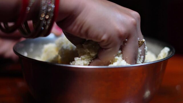 Indian Woman Hand Kneading Fresh Chhena Dough in Metal Bowl Close Up. Mashing Cottage Cheese Grains by Hand for Traditional Indian Dessert.