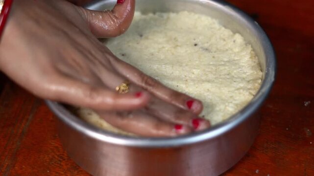 Pressing Raw Chhena Poda Cake Batter into Baking Tin Close Up. Hand Flattening Cottage Cheese Dough in Metal Mold for Indian Sweet. Indian Food Preparation. 