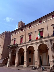 Obraz premium Historic brick palace with arched porticoes and the Italian flag
