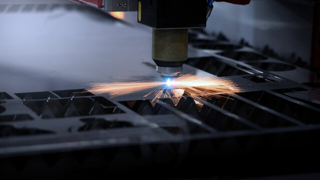 Laser cutting machine. High precision laser cutting robot processing sheet metal in factory. Ai automated CNC manufacturing technology creates intricate components with sparks accuracy and efficiency